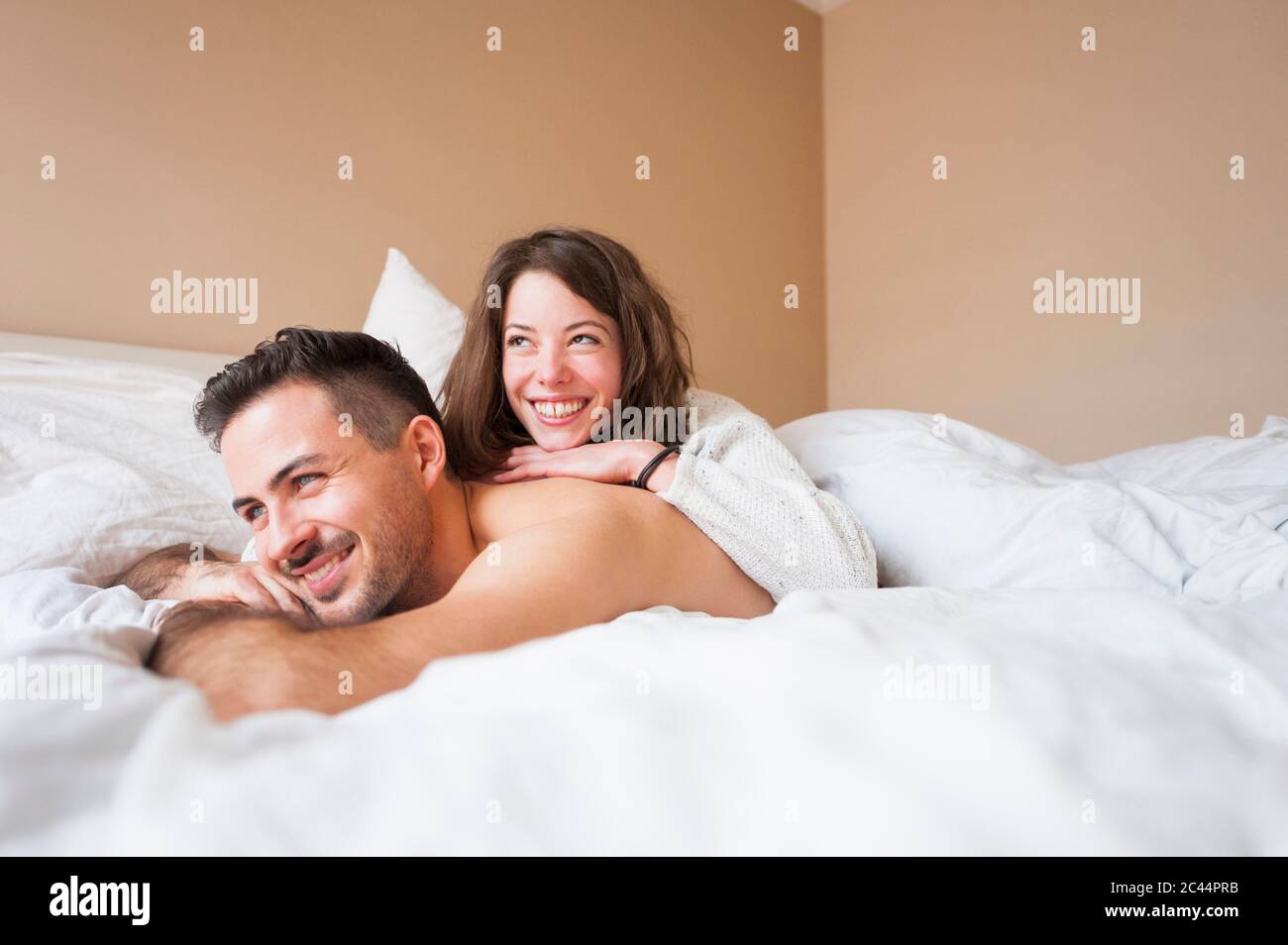 Nachdenkliches junges Paar, das zu Hause im Bett liegt Stockfoto