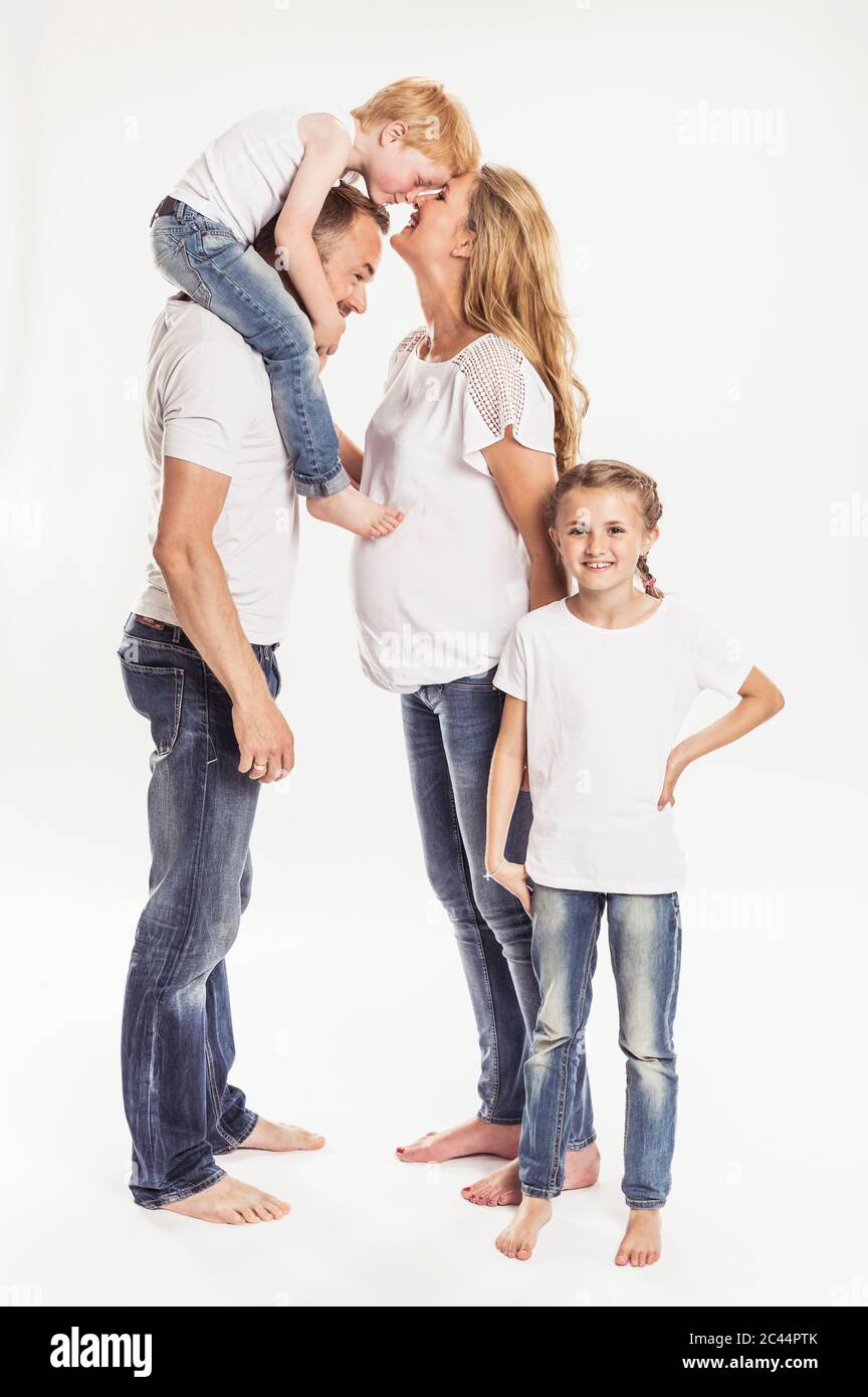 Schwangere Frau mit Ehemann und zwei Kindern vor weißem Hintergrund Stockfoto