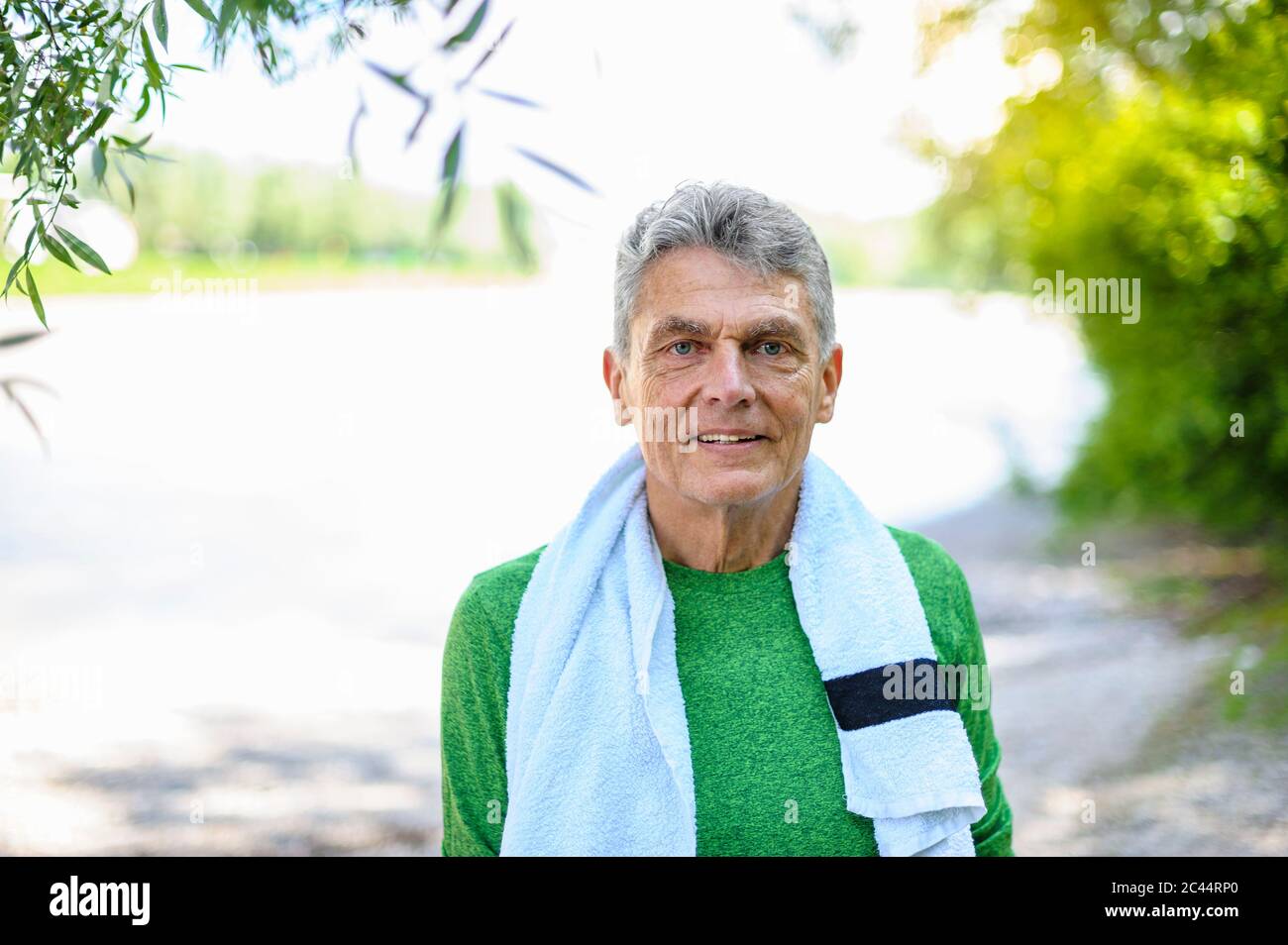 Porträt eines selbstbewussten älteren Mannes, der mit einem Handtuch im Park steht Stockfoto