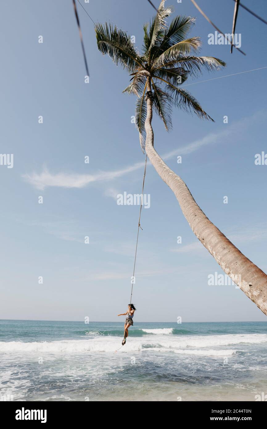 Volle Länge des Frau Schwingen von Palme am Strand gegen Himmel, Sri Lanka Stockfoto