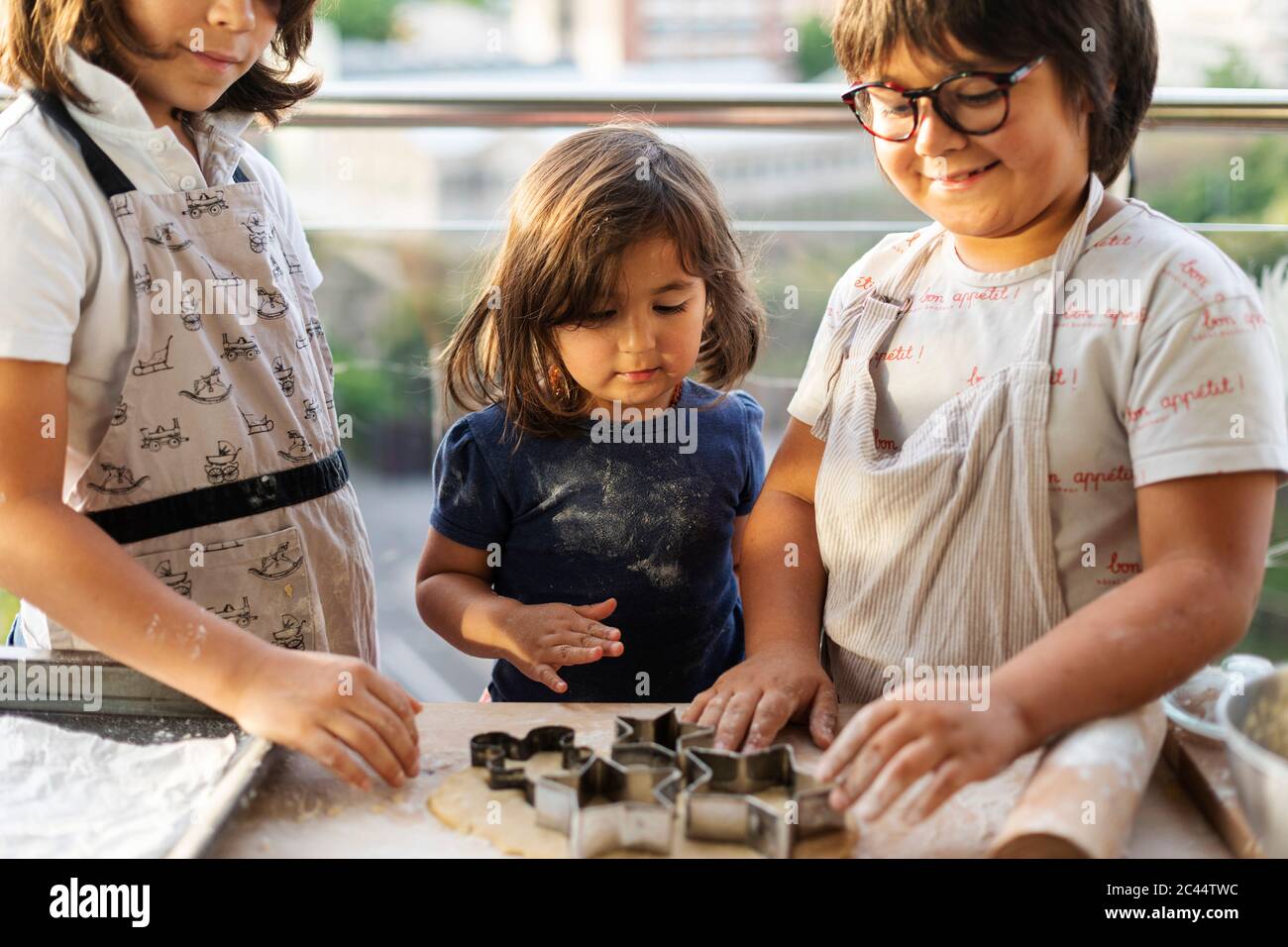 Drei Kinder schneiden Kekse aus Stockfoto