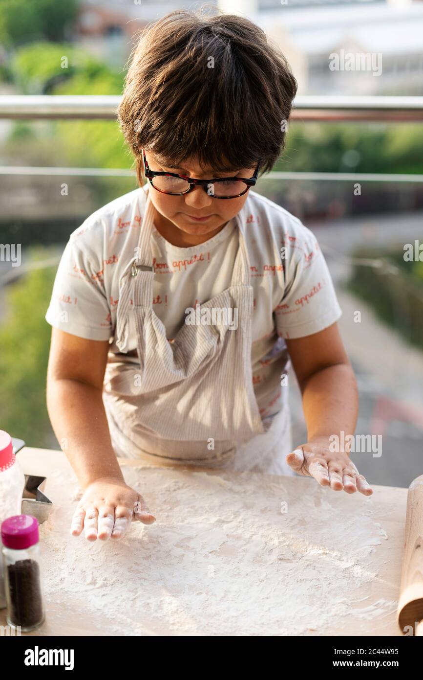 Kleiner Junge, der Mehl auf der Küchenunterfläche verteilt Stockfoto