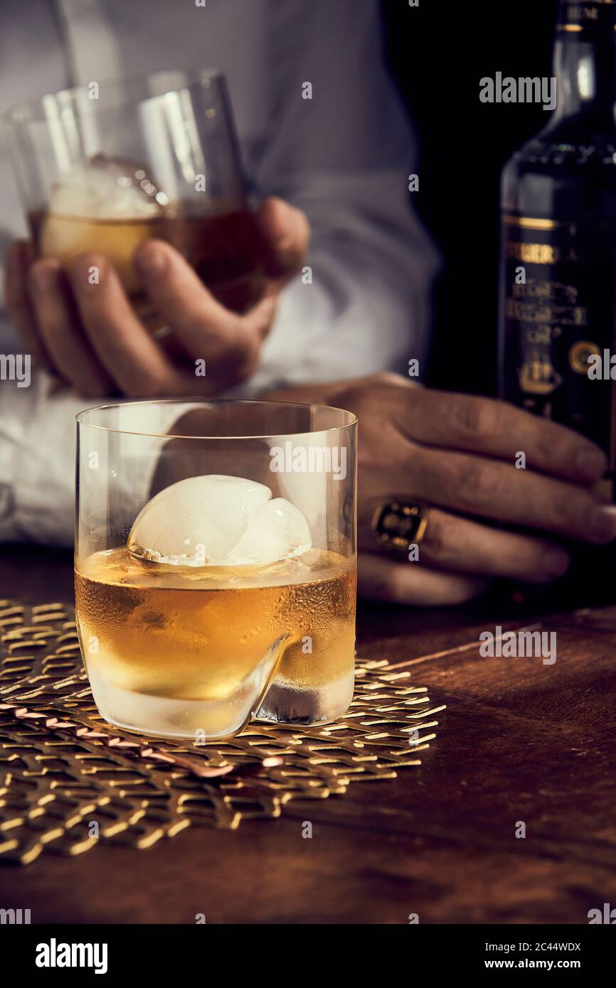 Scotch mit Eis, mans Hände im Hintergrund Stockfoto