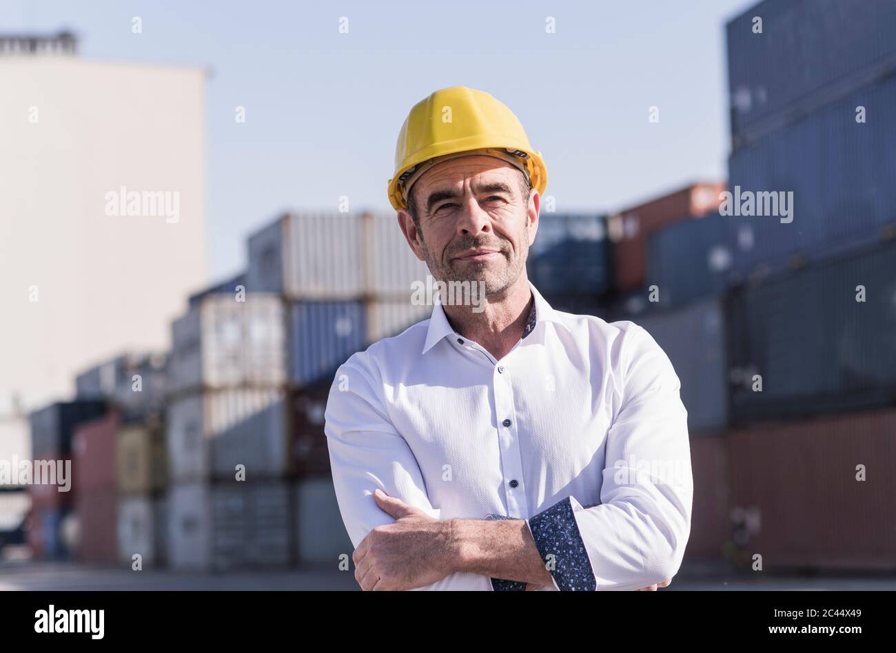 Porträt eines Geschäftsmannes mit Schutzhelm vor Frachtcontainern Stockfoto