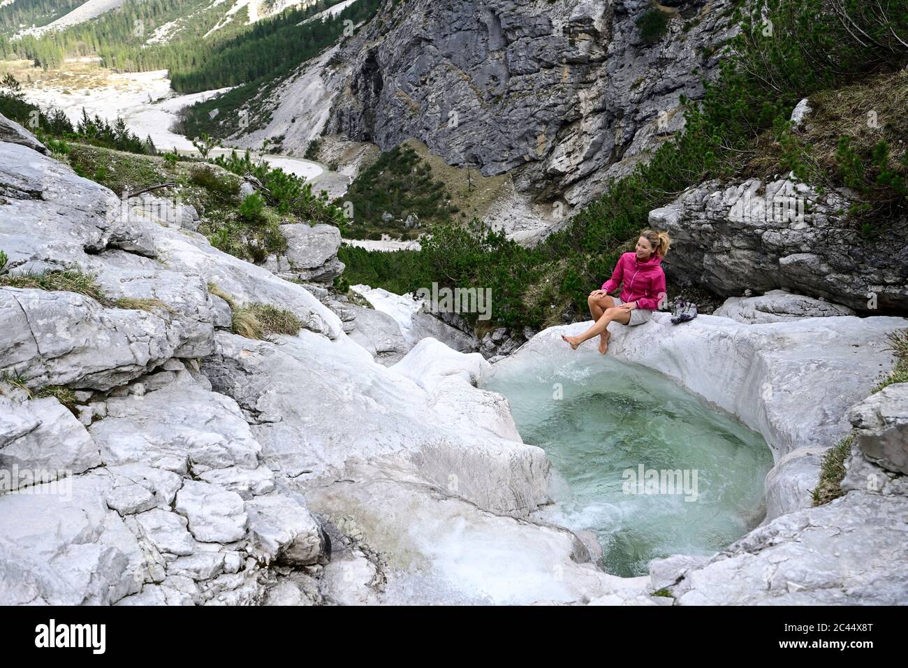 Weibliche Touristen genießen beim Planschen Wasser mit Bein im Bach gegen Berg Stockfoto