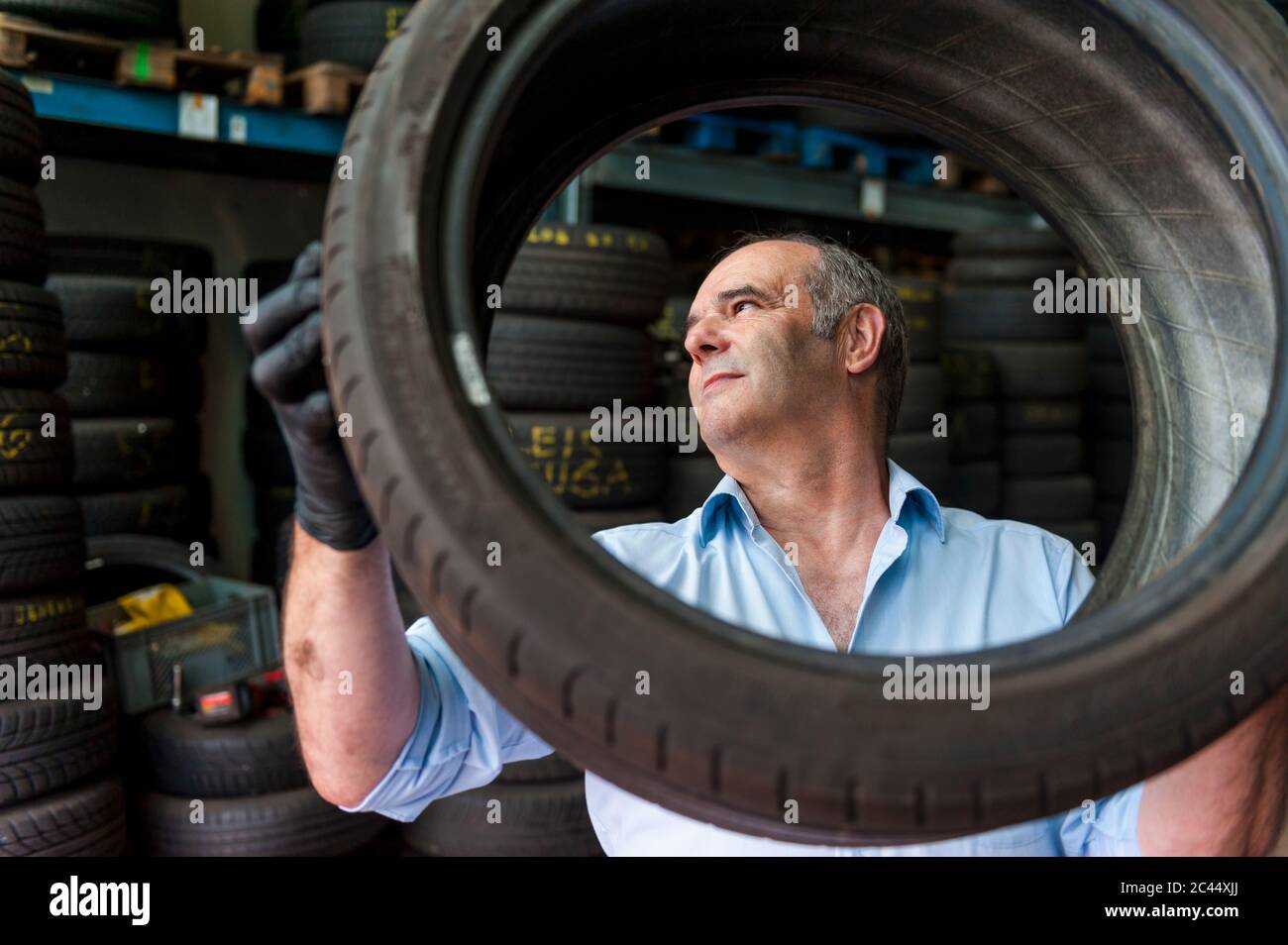 Leitender männlicher Unternehmer, der Reifen hält, während er im Geschäft arbeitet Stockfoto