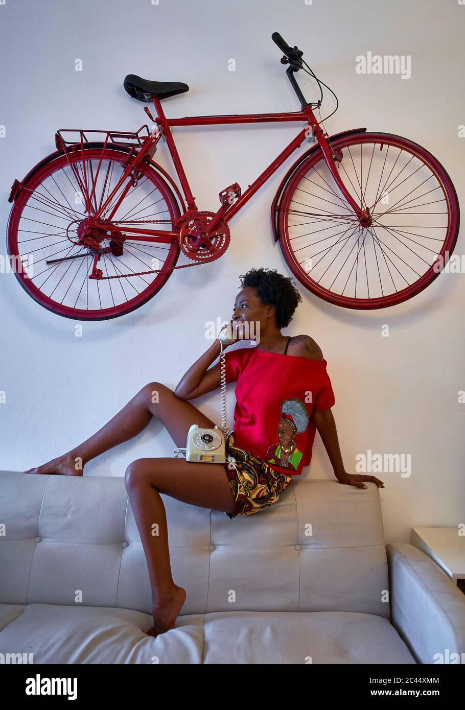 Frau mit altmodischen Festnetz-Telefon im Wohnzimmer zu Hause mit Fahrrad an der Wand hängen Stockfoto