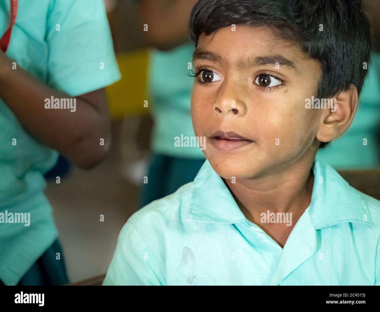 PUDUCHERRY, INDIEN - DEZEMBER CIRCA, 2018. Unidentifizierte arme indische Junge Porträt suchen ernst mit grünen Regierung Uniform im Klassenzimmer Stockfoto