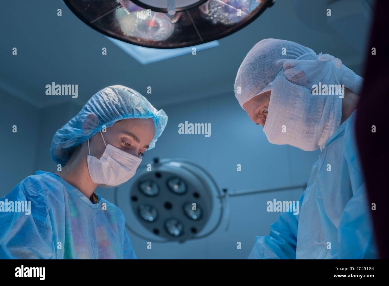 Kinderchirurgen führen urologische Operationen durch. Ein Mann und eine Frau in einer Maske und einem blauen sterilen Kleid im Operationssaal. Ansicht von unten Stockfoto