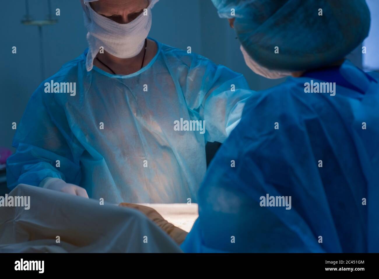 Kinderchirurgen führen urologische Operationen durch. Ein Mann und eine Frau in einer Maske und einem blauen sterilen Gewand im Operationssaal. Stockfoto