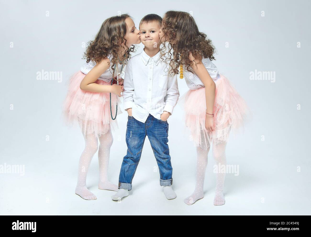 Zwei kleine Mädchen küssen einen Jungen. Schöne Foto-Session im Studio, Weiß zurück Stockfoto