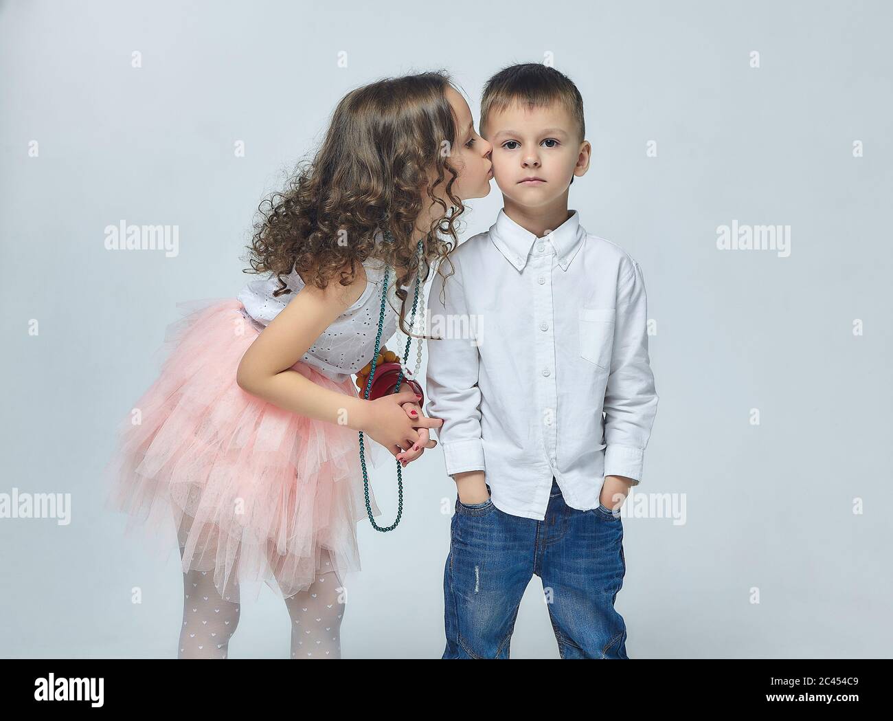 Kleines Mädchen küsst einen Jungen. Schöne Foto-Session im Studio, Weiß zurück Stockfoto