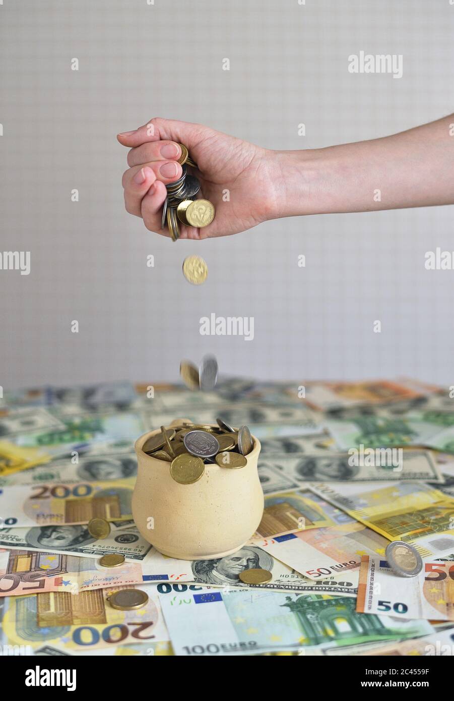 Münzen fallen in den Becher. Münzen gießen aus einer weiblichen Hand Stockfoto