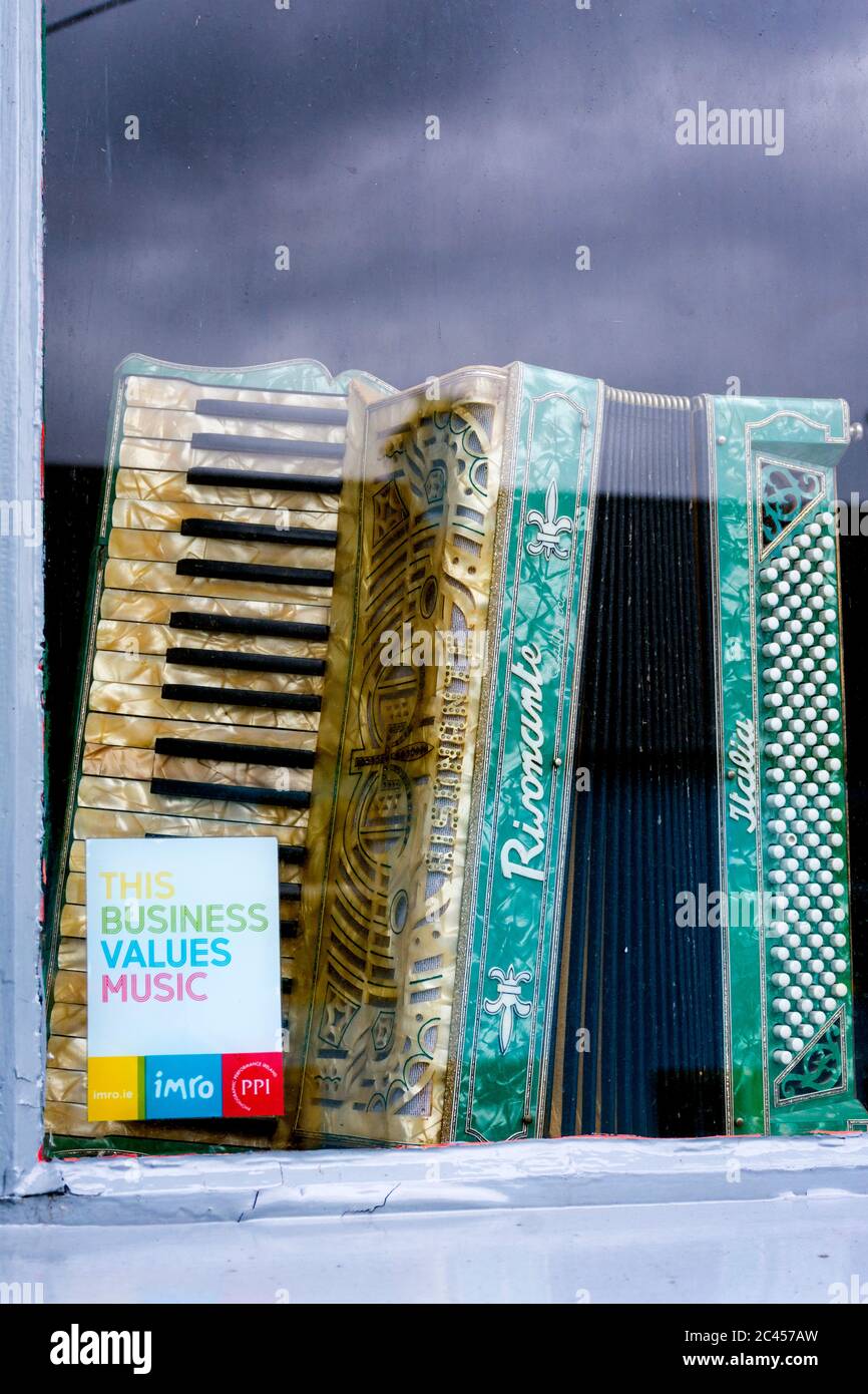 Fenster einer traditionellen Musikbar mit IMRO-Sticker und antikem Klavierakkordian Stockfoto