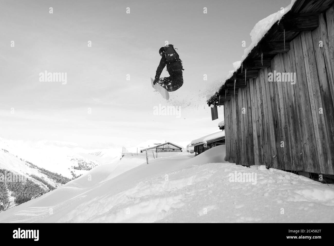 Snowboarder springt über eine Scheune in Hochfügen, Tirol, Österreich Stockfoto