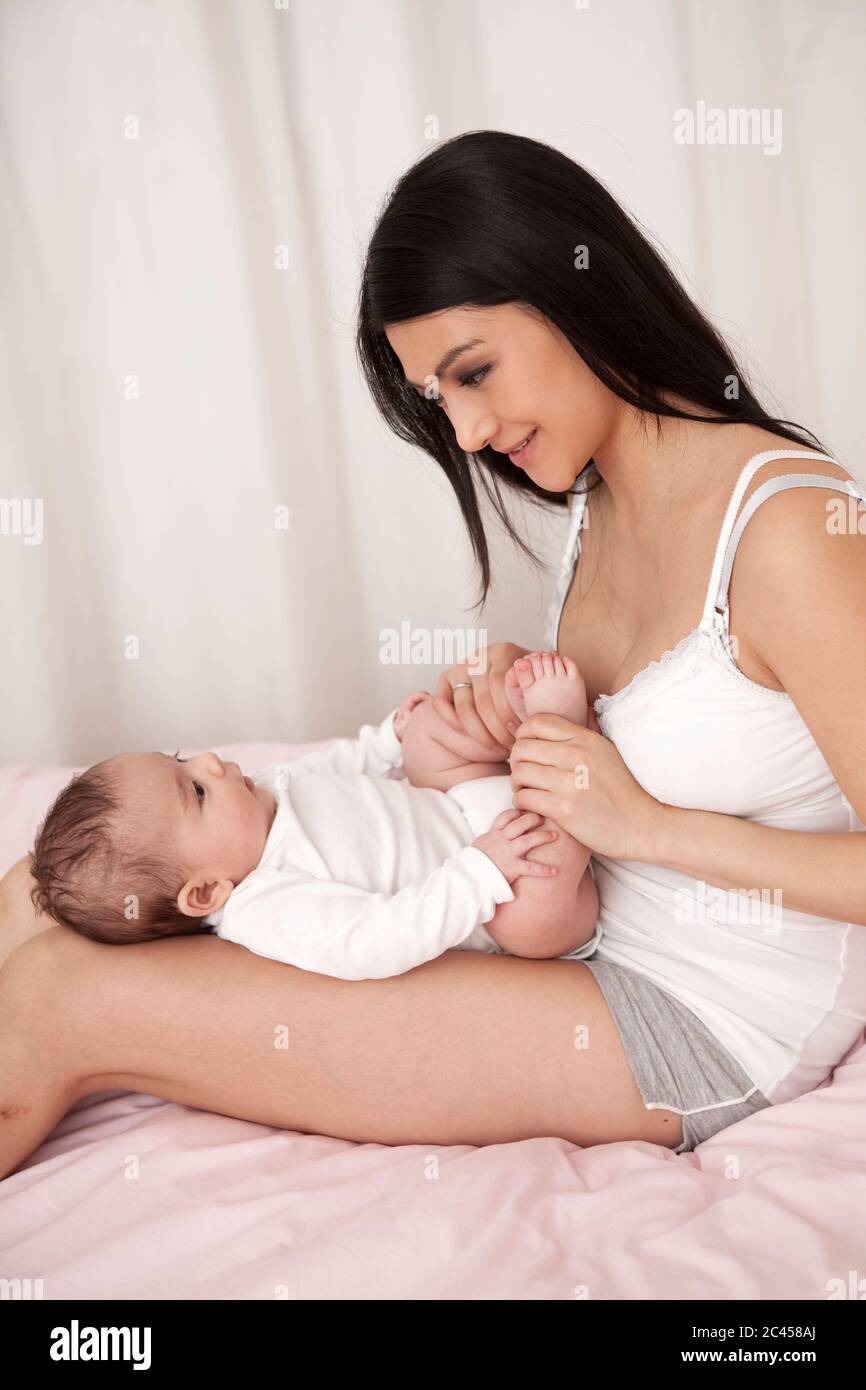 Mutter spielt mit Baby im Bett Stockfoto