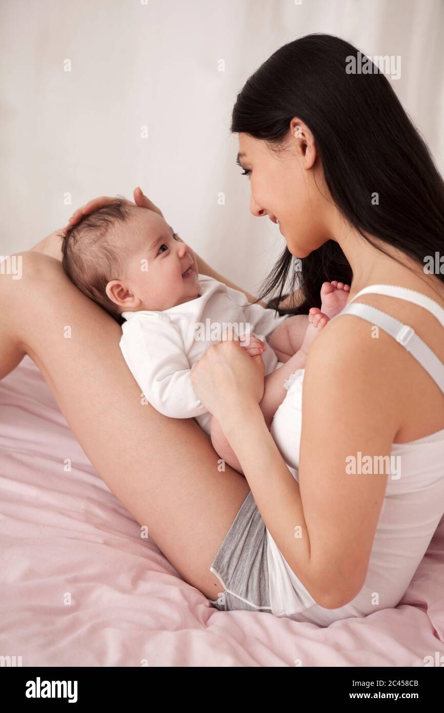 Mutter spielt mit Baby im Bett Stockfoto