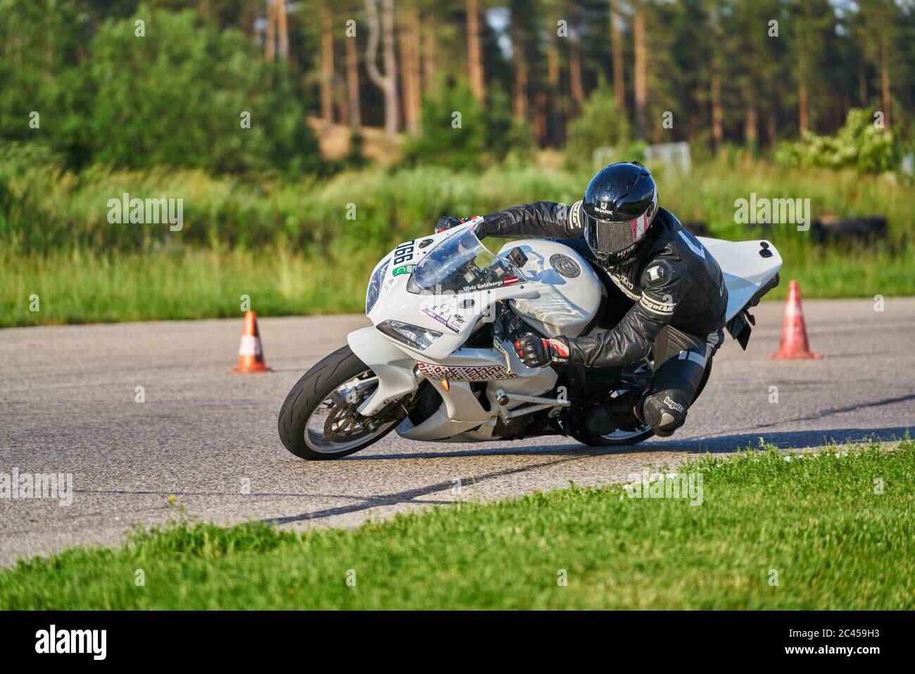 11-05-2020 Riga, Lettland. Motorbiker auf einer Rennstrecke, die um eine Ecke mit einem Rennkurs Bordstein hinter sich rast. Stockfoto