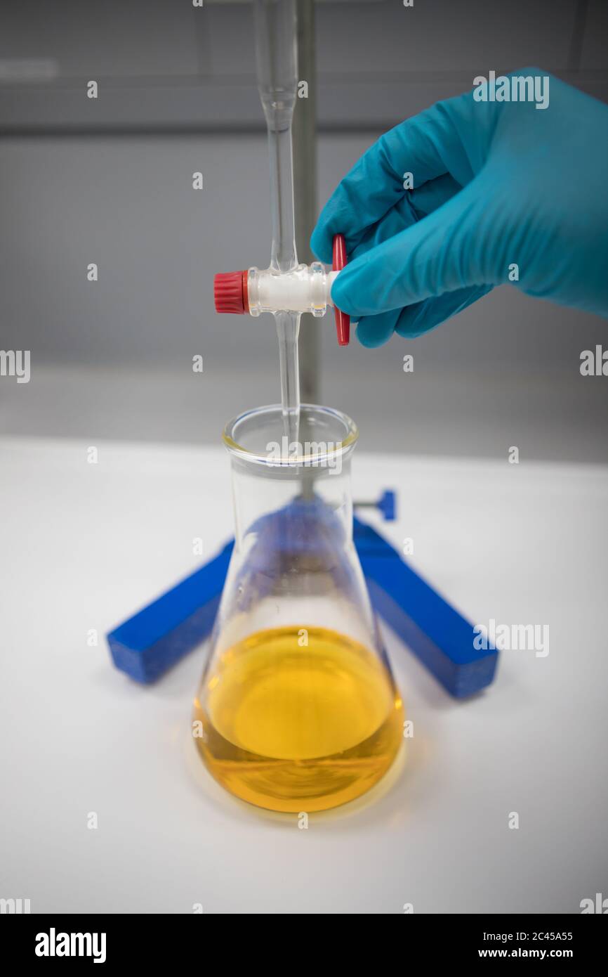 Titration einer Lösung mit einem orangefarbenen Indikator. Chemiker in einem pharmazeutischen Labor Stockfoto