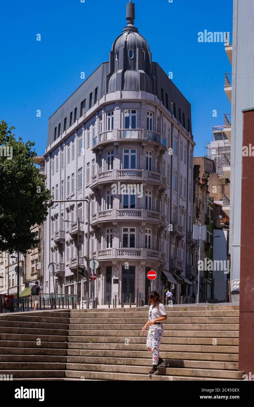 Porto, Portugal - EINE Frau, die auf Steintreppen vor einem wunderschönen neoklassischen Steingebäude mit ornaierten Balkonen geht Stockfoto