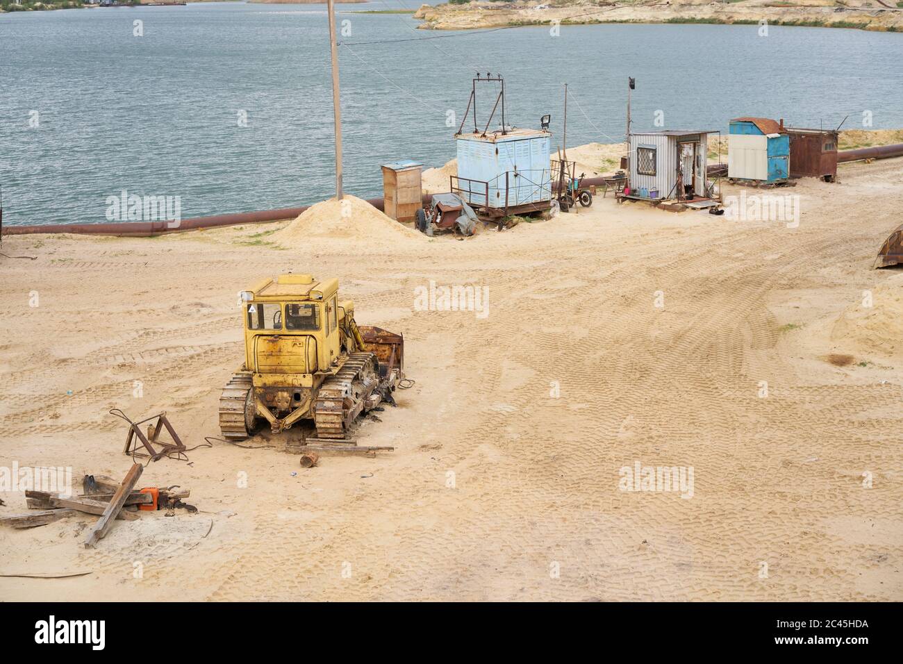 Sandbruch Bergbau Industrie Ausrüstung Bagger Traktor stehend Sand Land in der Nähe See Wasser Industrielle Aktivität Mine Betrieb Sommer sonnigen Tag. Ökologie Problem nicht erneuerbare Ressourcen der Erde Stockfoto