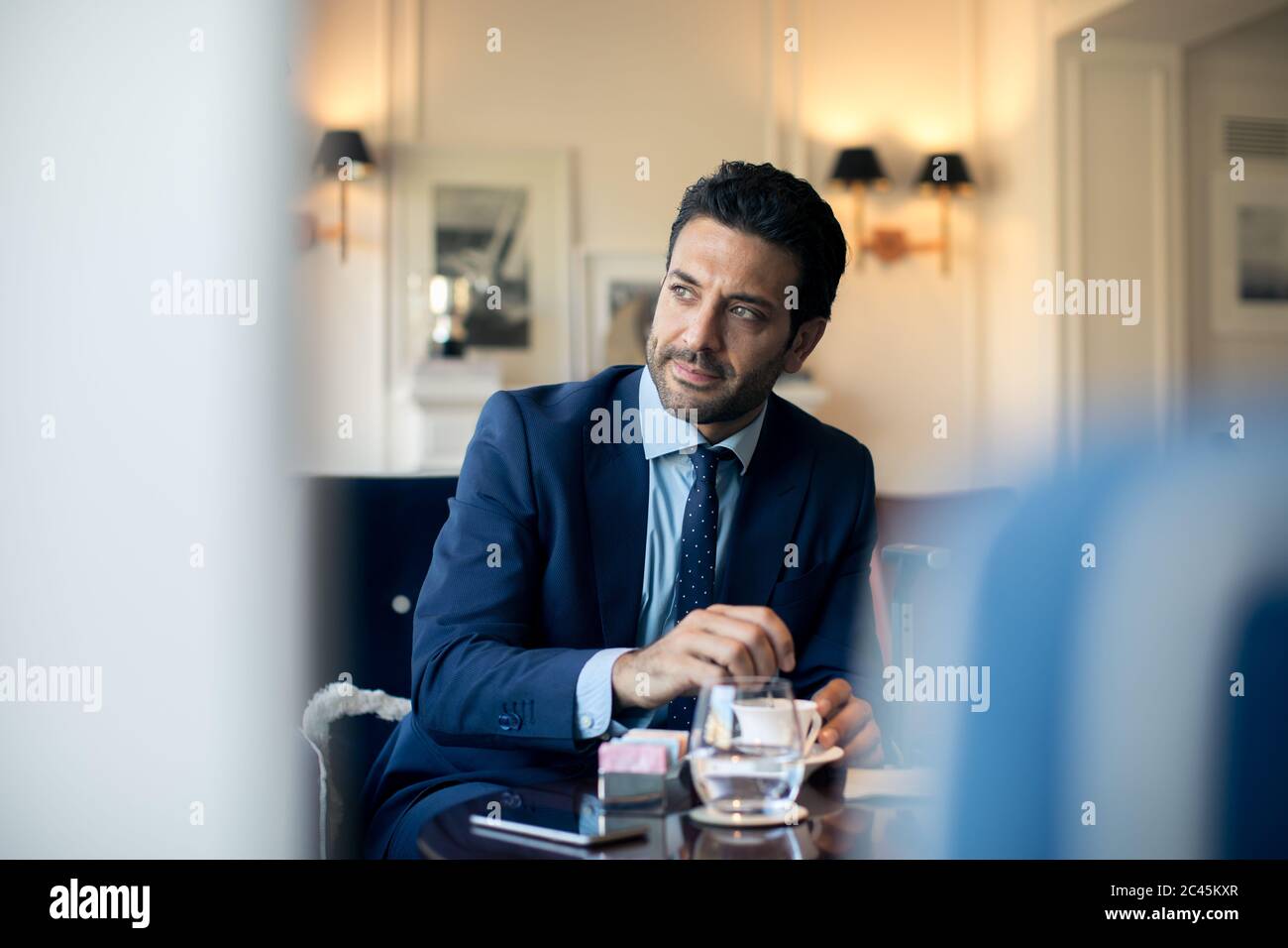 Geschäftsmann sitzt an einem Tisch, rührende Tasse Kaffee. Stockfoto