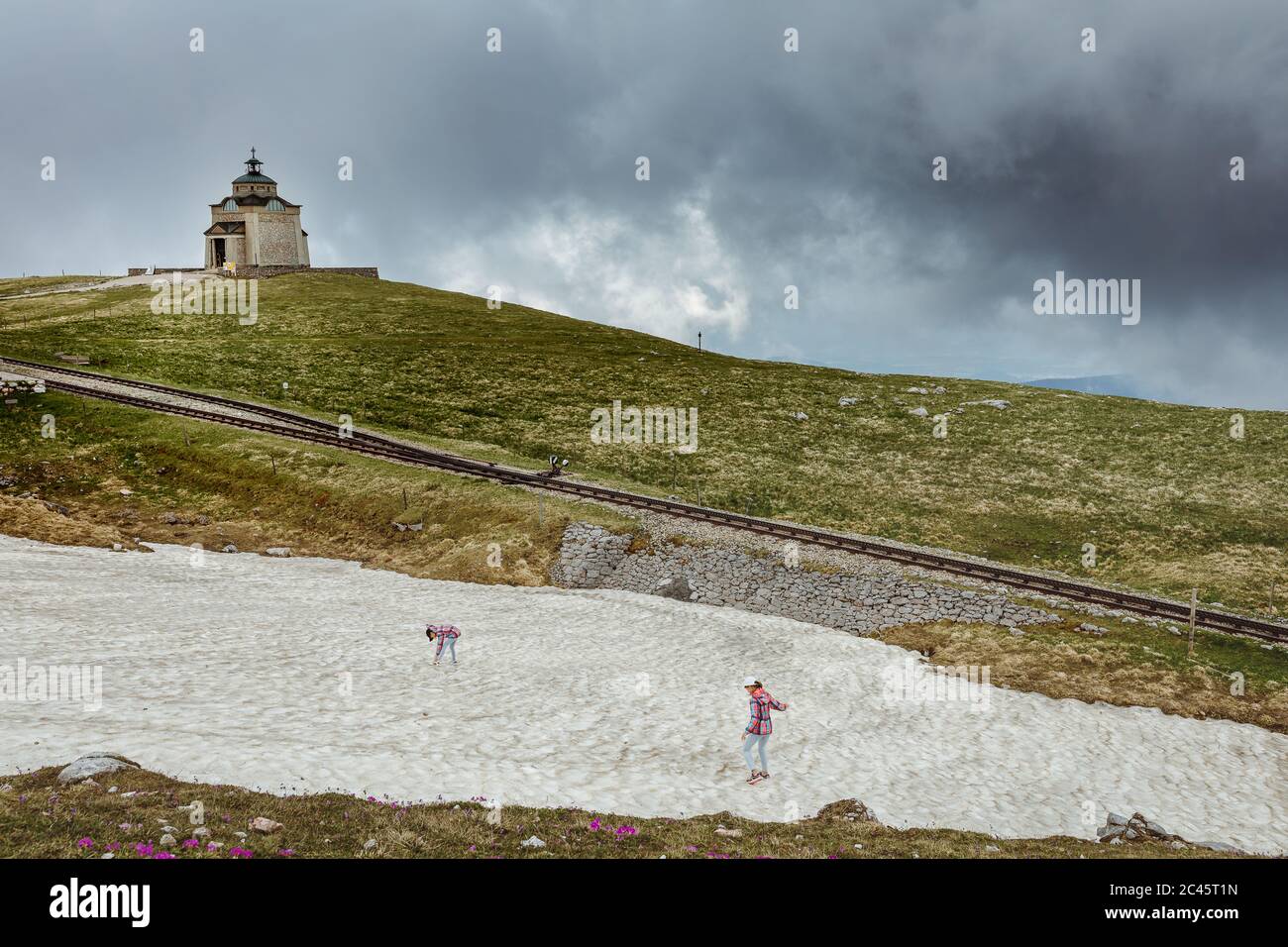 Zwei junge Mädchen spielen im restlichen Frühlingsschnee in alpiner Bergkulisse Stockfoto