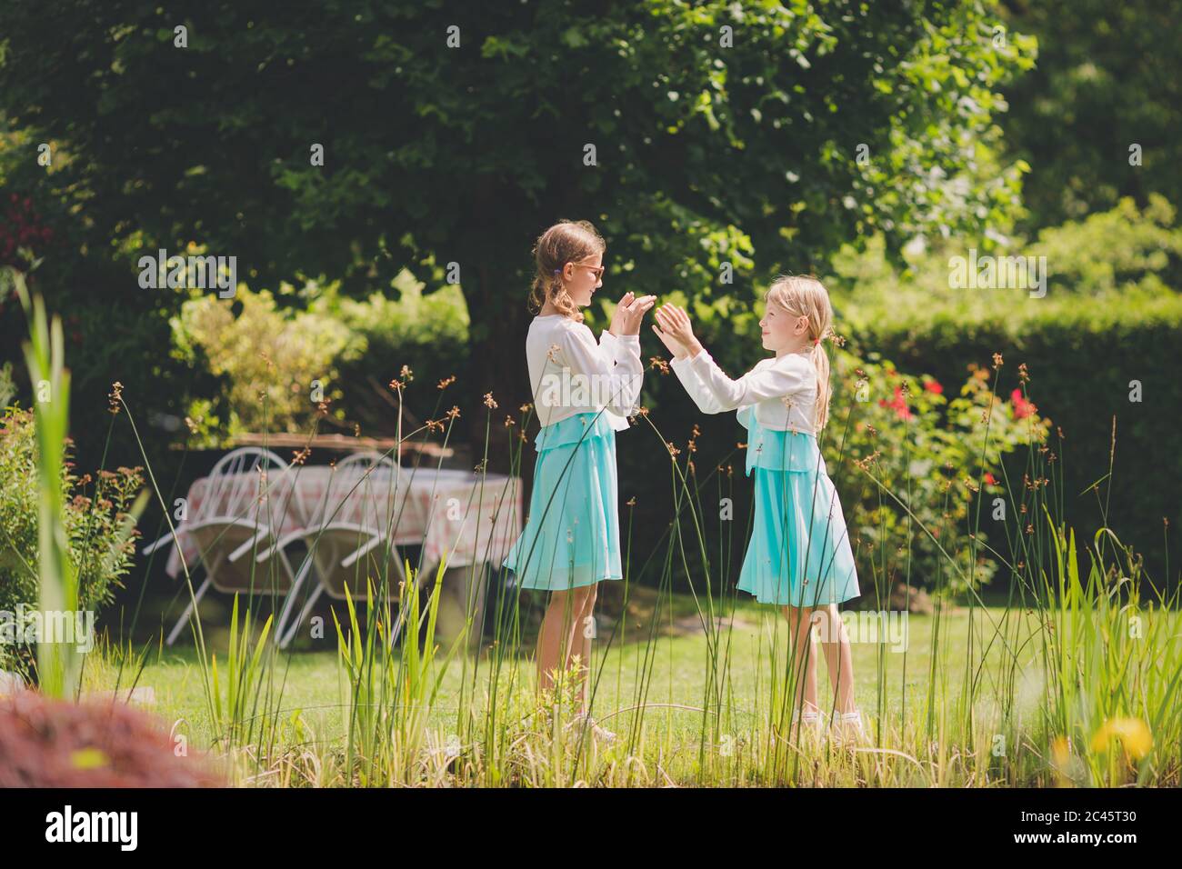 Zwei junge kaukasische Mädchen spielen Hand klatschen Spiele im grünen Garten Stockfoto