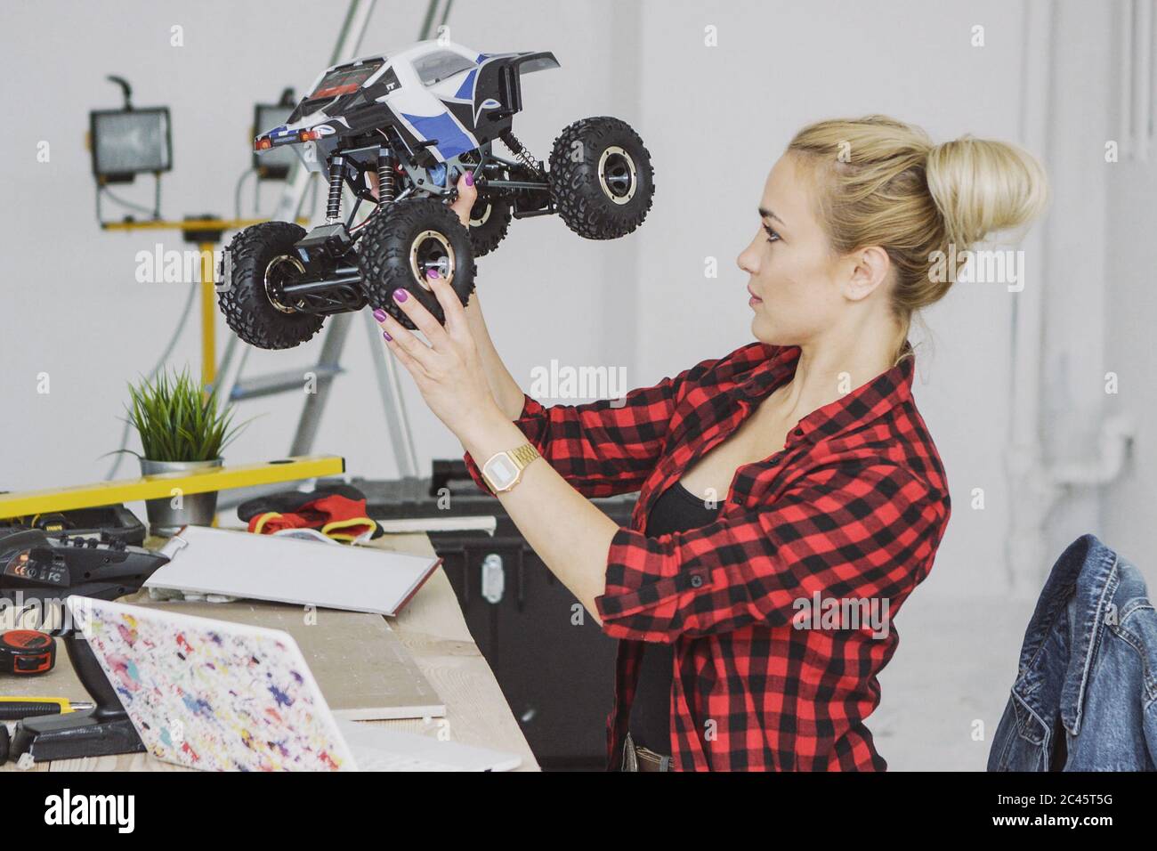 Frau untersucht funkgesteuertes Auto in der Werkstatt Stockfoto