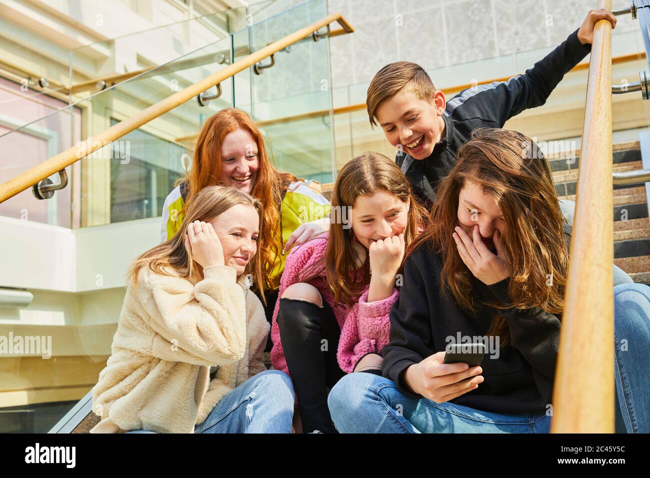 Eine Gruppe von Mädchen im Teenageralter in einem Einkaufszentrum, die ihre Mobiltelefone überprüfen. Stockfoto