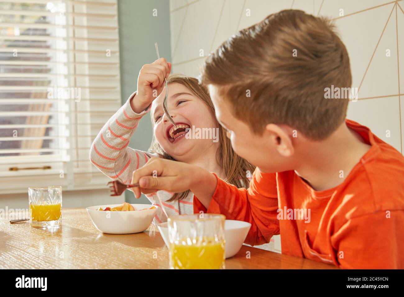 Junge und Mädchen sitzen am Küchentisch, essen Frühstück. Stockfoto