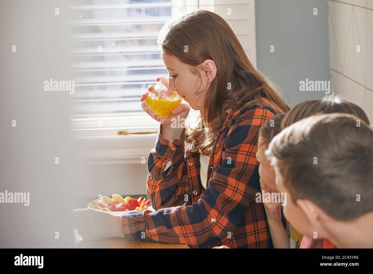 Teenager Mädchen auf dem Sofa sitzen, Frühstück essen, Orangensaft trinken. Stockfoto
