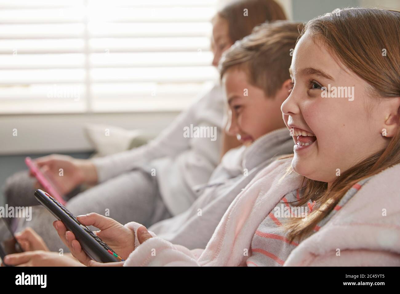 Gruppe von Kindern, die auf einem Sofa in ihrem Schlafanzug sitzen und Fernsehen. Stockfoto