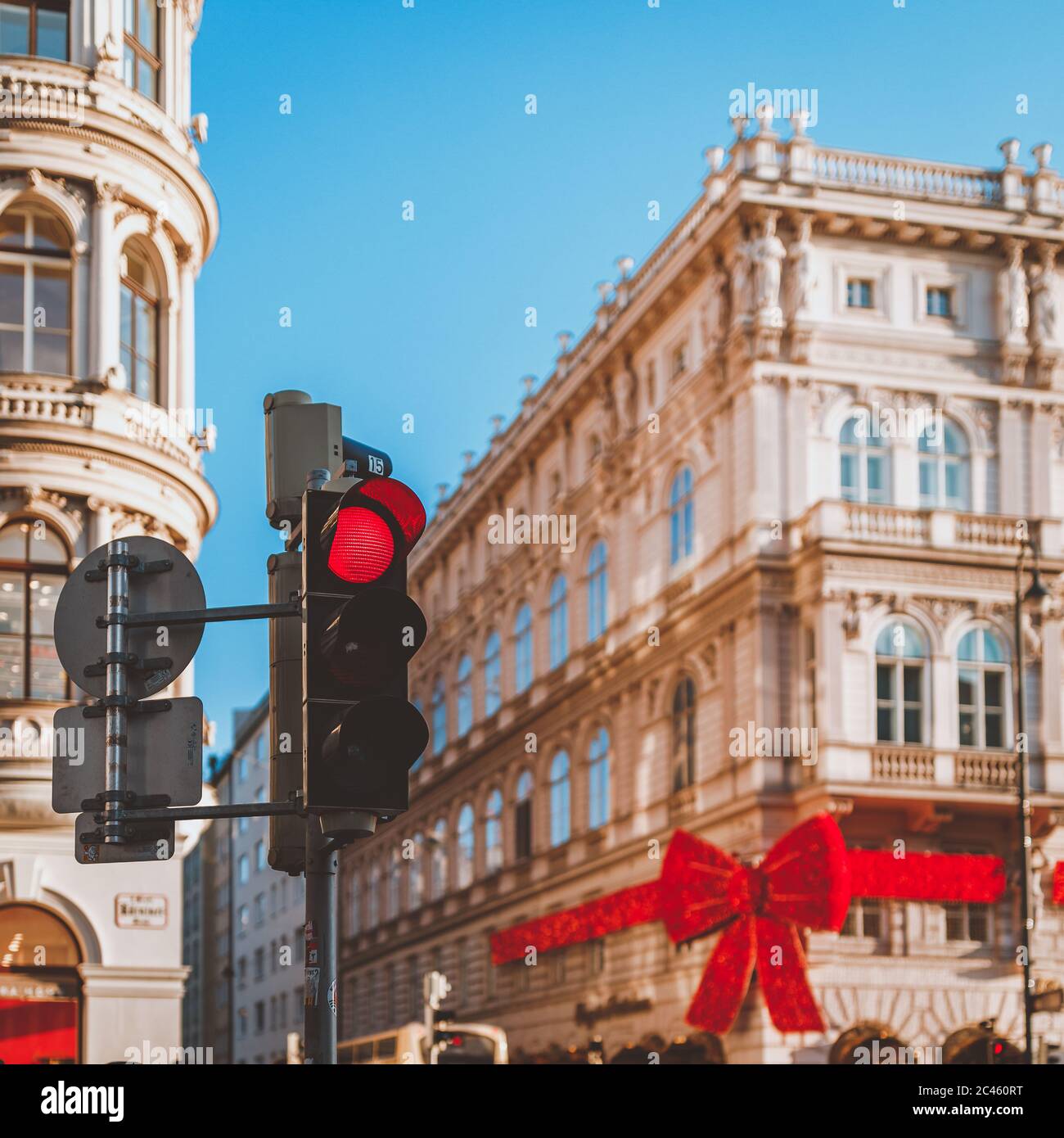 Selektiver Fokus von riesigen dekorativen roten Weihnachtsbogen auf Gebäude mit roter Ampel Stockfoto