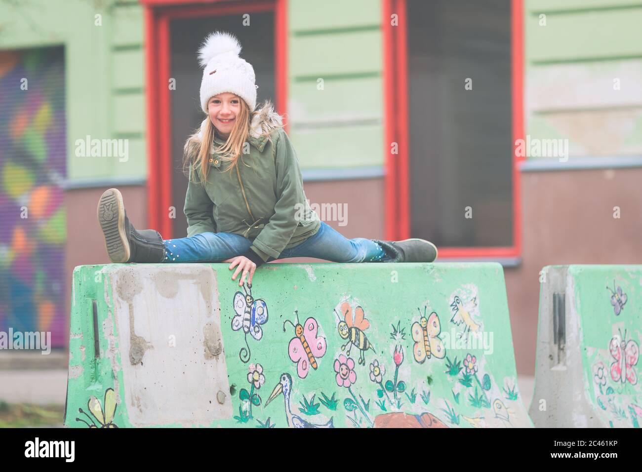 Junge Gymnastikerin, Grundschulalter, Splits auf einer Betonschutzbarriere in der Straße Stockfoto