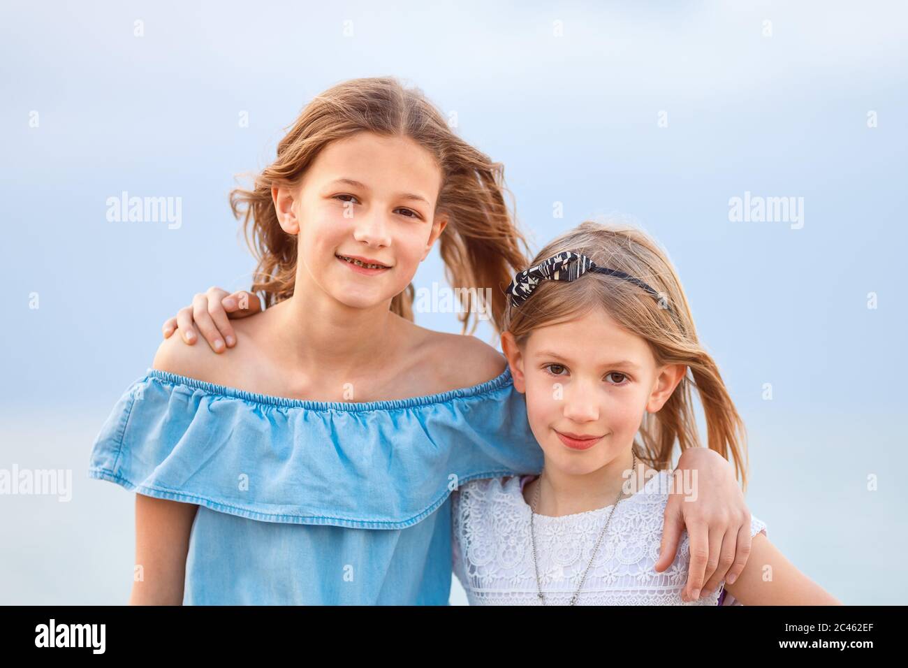 Zwei junge Mädchen in legerer Sommerkleidung, die in einer Küstenregion lächelnd auf die Kamera blicken Stockfoto