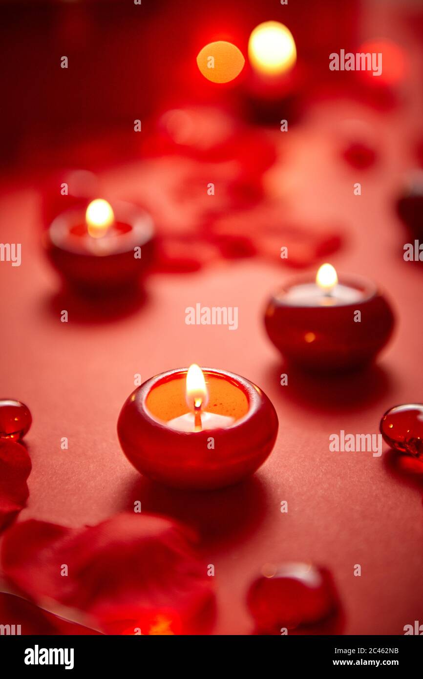 Romantische Dekoration für das Abendessen. Rote Kerzen, Blütenblätter, auf dem Tisch Stockfoto