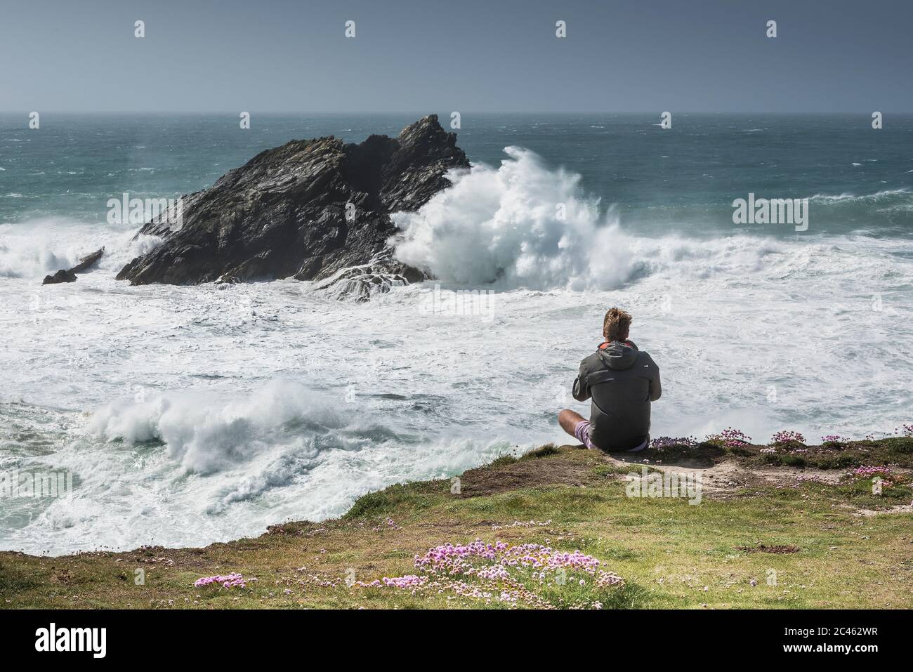 Ein Tourist, der die dramatische Aussicht von Pentire Point East an der Küste von Newquay in Cornwall genießt. Stockfoto