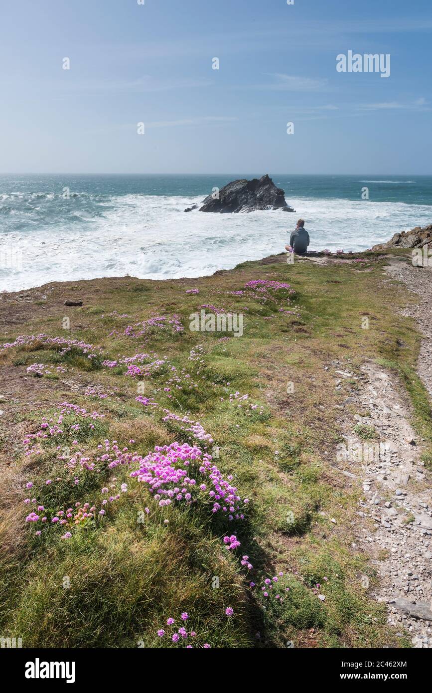 Ein Tourist, der die dramatische Aussicht von Pentire Point East an der Küste von Newquay in Cornwall genießt. Stockfoto