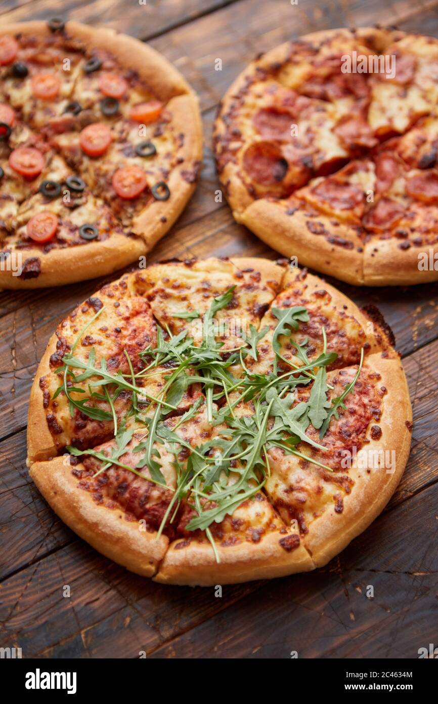 Zusammensetzung von drei verschiedenen Arten Pizza auf hölzernen Tisch Stockfoto