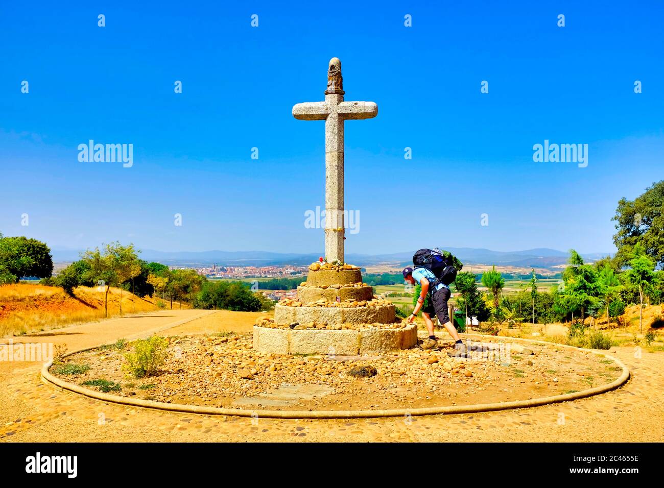 Pilger, der einen Felsen auf dem Cruceiro de Santo Toribio in Justo de la Vega auf dem Jakobsweg (Camino de Santiago), Kastilien und León, Spanien, legt Stockfoto