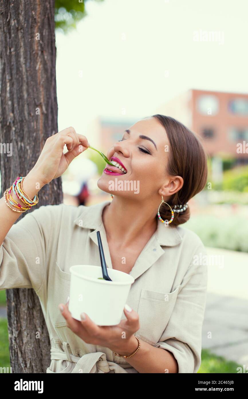 Junge Latina Frau genießt es, frischen Salat im Park zu essen, Diät Stockfoto