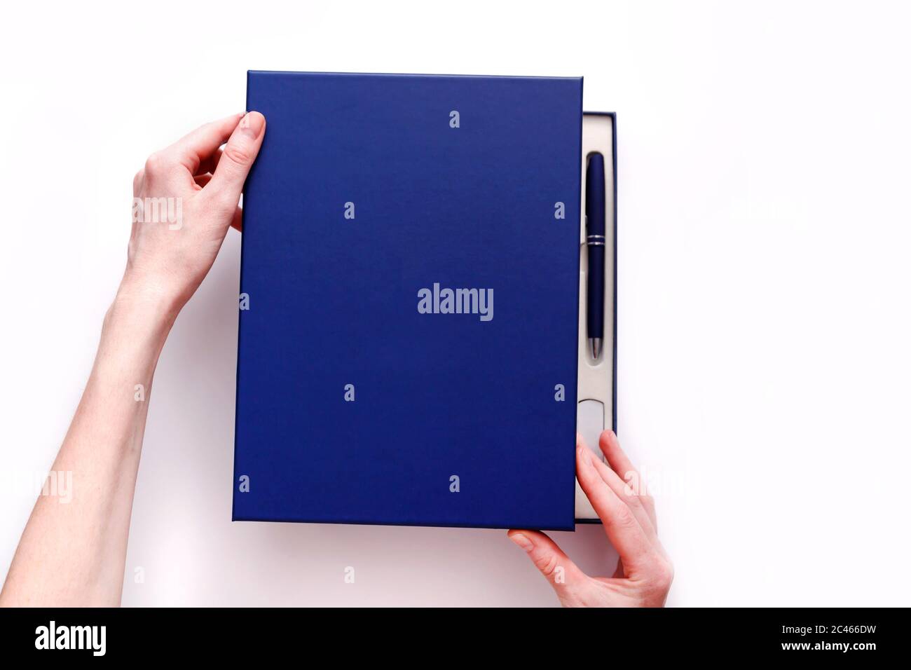 Frau Hände öffnen Abdeckung des Corporate Style Box mit Stift, Flash-Laufwerk und Notebook isoliert auf weißem Hintergrund. Blick von oben Stockfoto