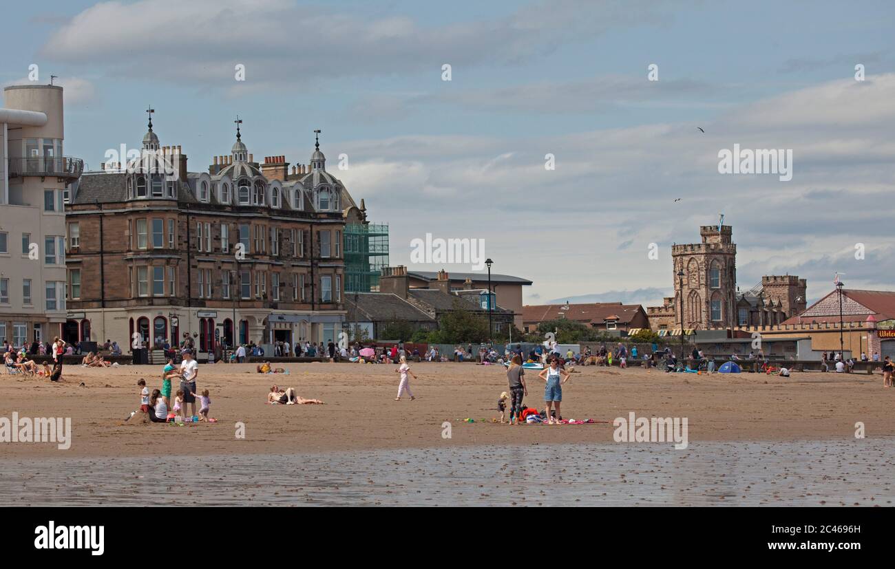 Portobello, Edinburgh, Schottland, Großbritannien. 24. Juni 2020. Das heiße Wetter brachte Familien raus, aber am Meer war nicht viel los, am Strand und an der Promenade gab es viel Platz, um sich in sozialer Distanz zu halten. Leute auf verschiedenen Paddelbrettern und Schlauchboote und andere mit Picknicks am Sandstrand. Stockfoto