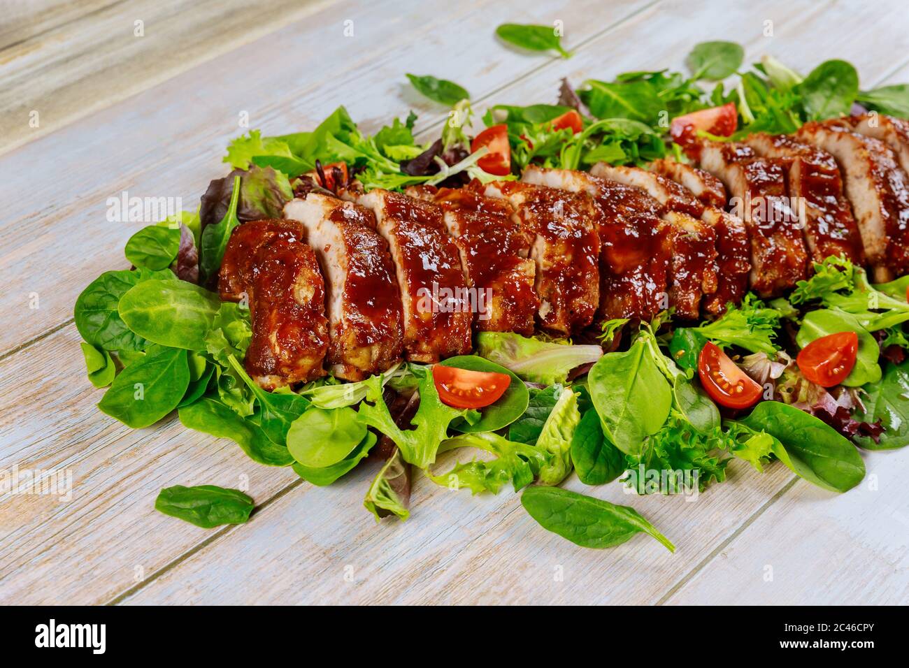 BBQ Schweinefilet oder Filet auf grünen Blättern mit Tomaten. Stockfoto
