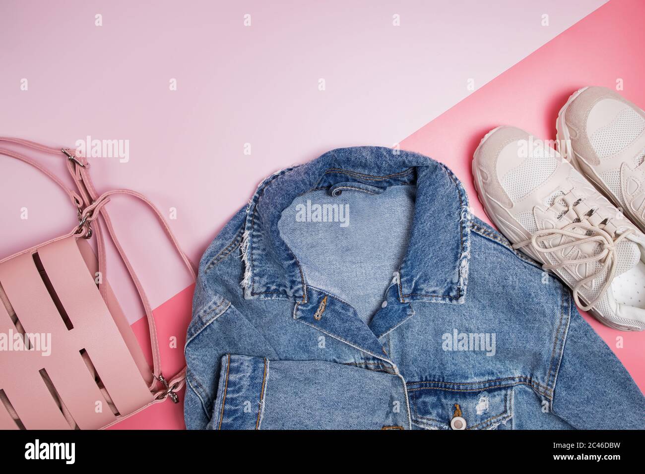 Jeansjacke, Tasche und Sneaker auf rosa Hintergrund Stockfoto