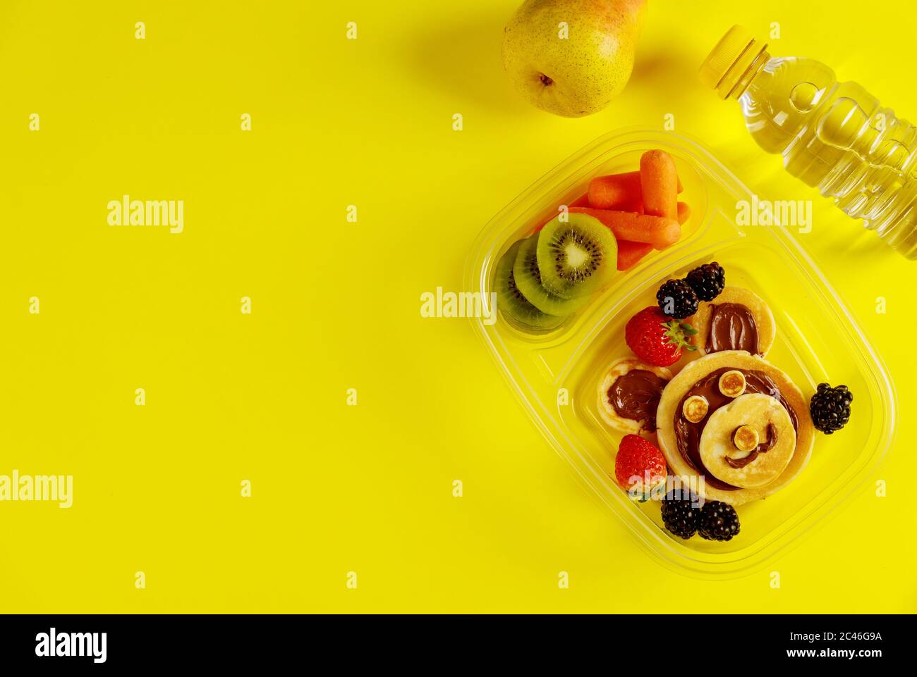 Leckere Speisen in Lunchboxen mit Wasser und Birne auf gelbem Hintergrund. Stockfoto