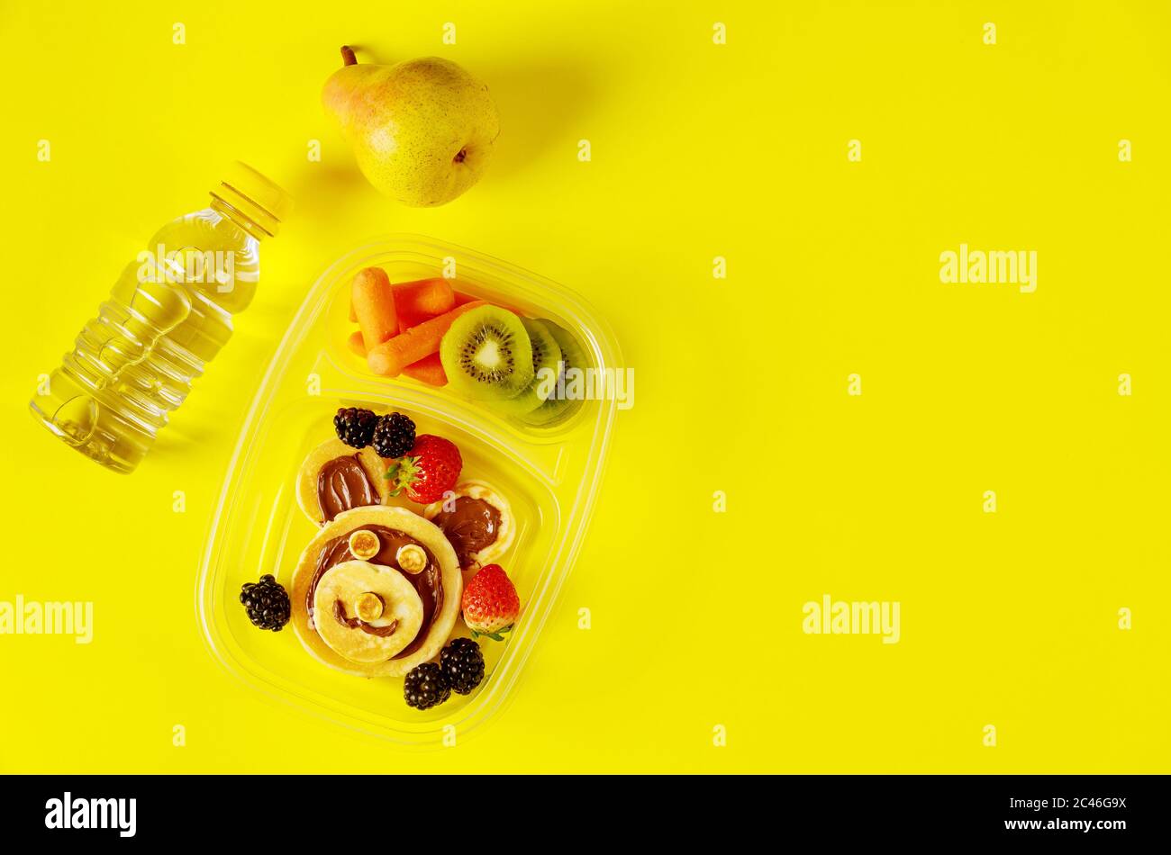 Kinderessen in Lunchboxen mit Wasser und Birne auf gelbem Hintergrund. Stockfoto