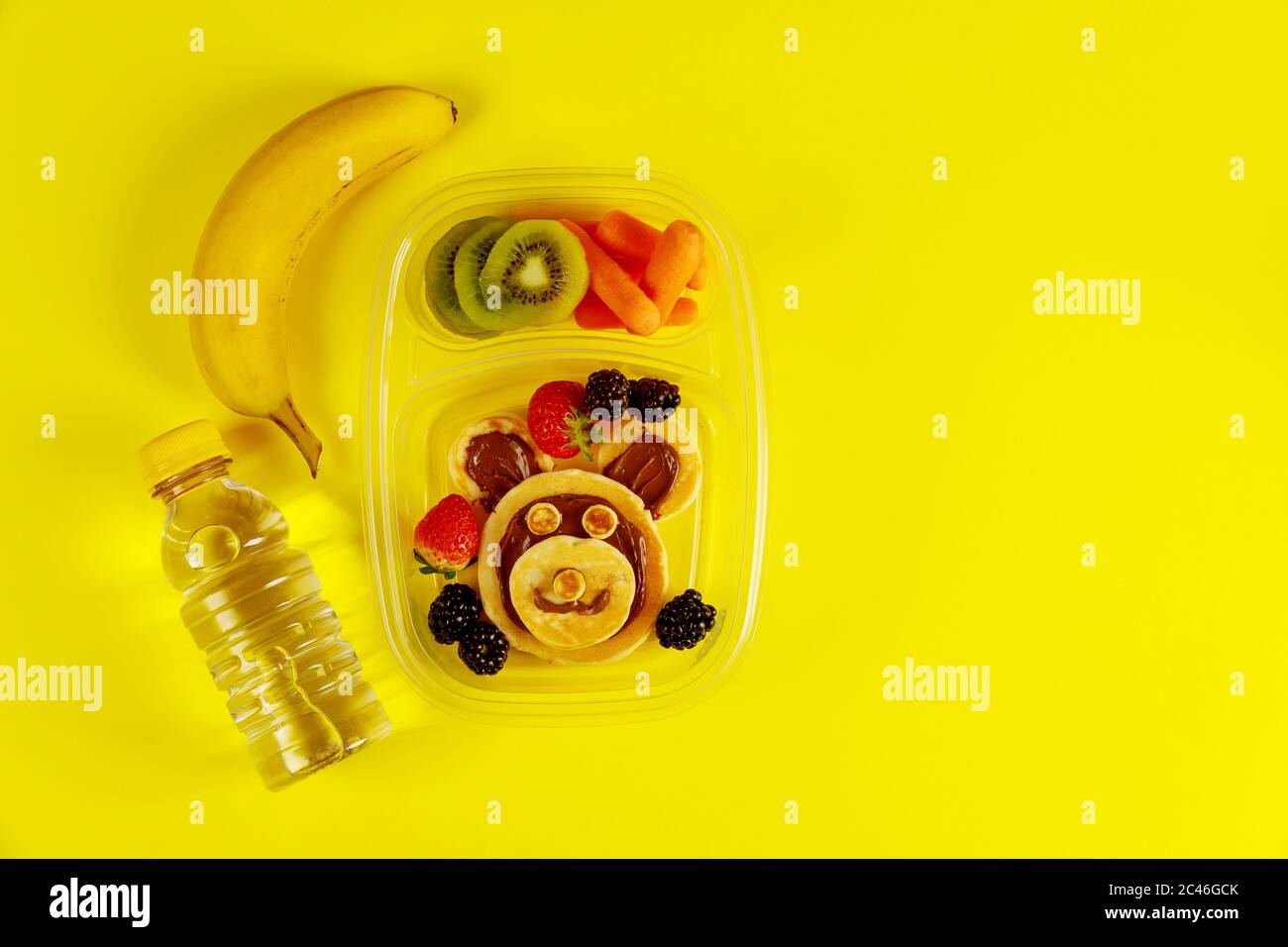 Leckeres Essen in Lunchboxen mit Wasser und Banane auf gelbem Hintergrund. Stockfoto