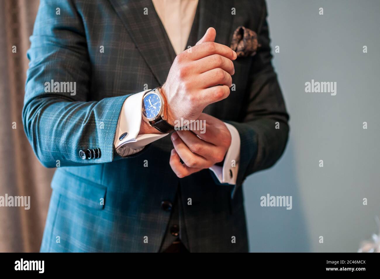 Der Bräutigam legt eine Uhr an sein Handgelenk Stockfoto